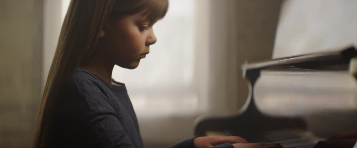 Young girl with long hair playing a piano indoors