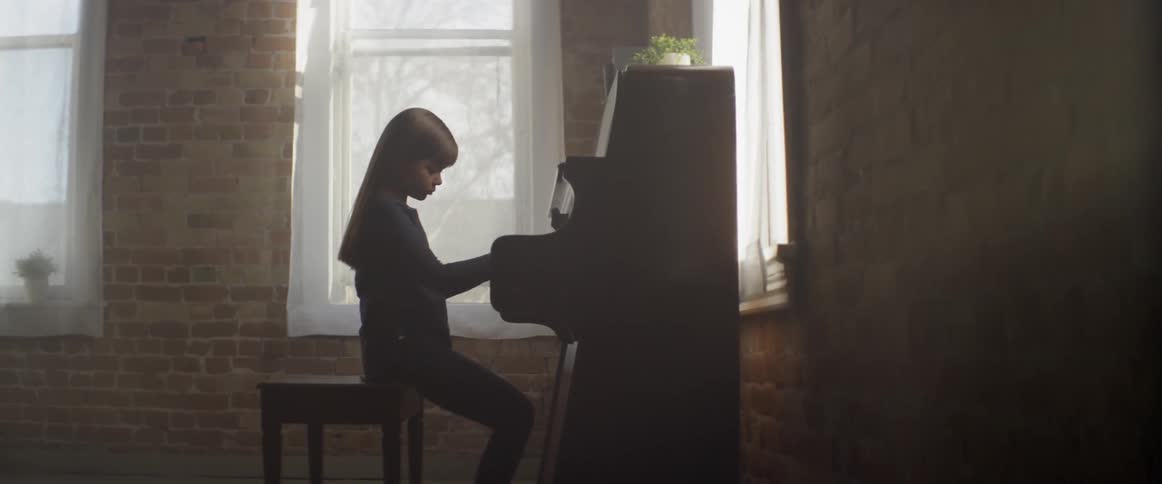 A young girl plays a piano