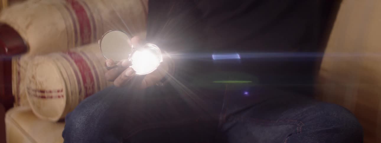 Man reflects light off a compact mirror