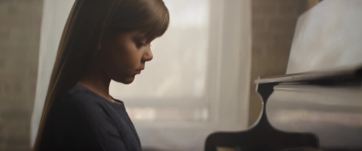A girl plays a piano gracefully in the evening light