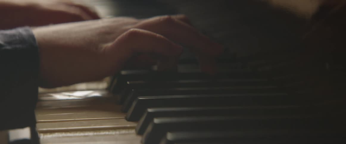 A person's hands are reflecting off the shiny piano as they play