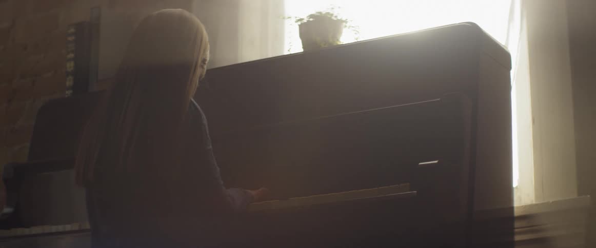 A child is sitting and playing the piano