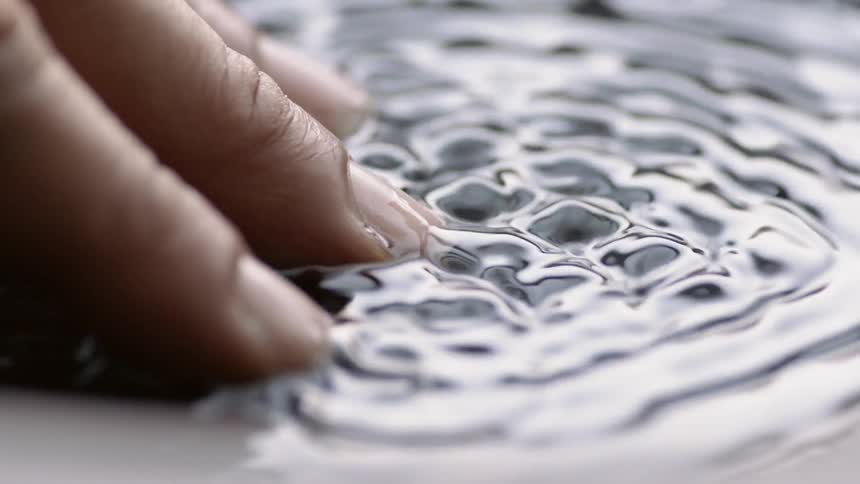 A person places their fingers in liquid as it vibrates