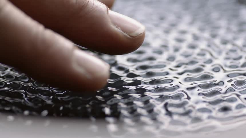 A person touches vibrating fluid