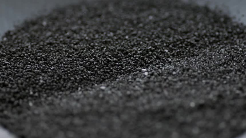 Black sand vibrates in a pile