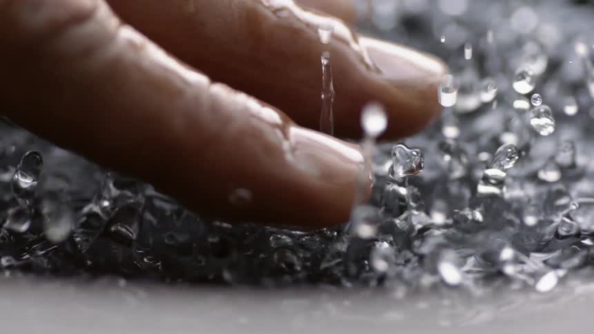 Hand touches vibrating water droplets