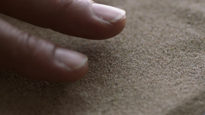 A man holds his hand above vibrating sand