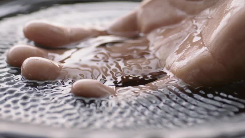 A man places his hand into vibrating water