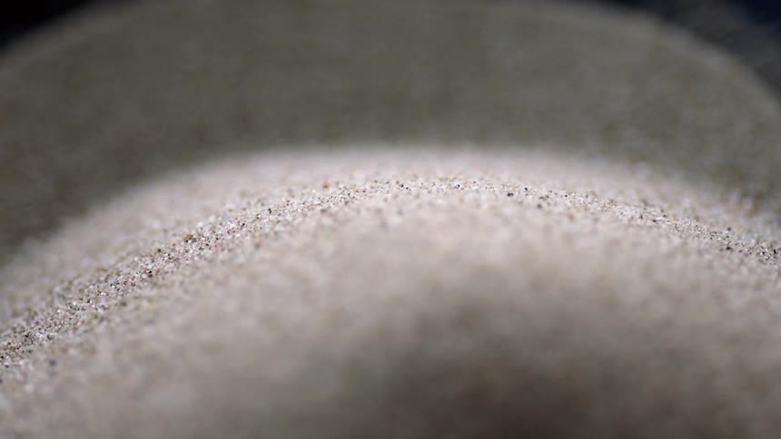 The sand is vibrating in the dark container