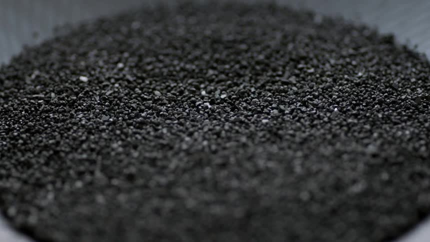 Small black pebbles are vibrating on a machine