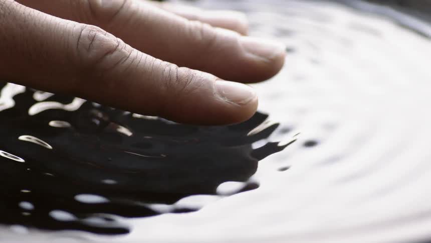 Person touches vibrating liquid
