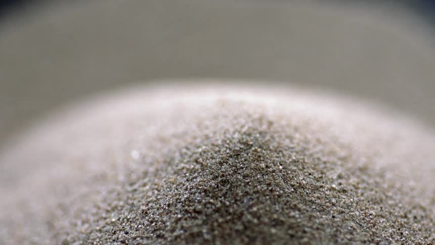 A mound of sand with grains trickling down the sides