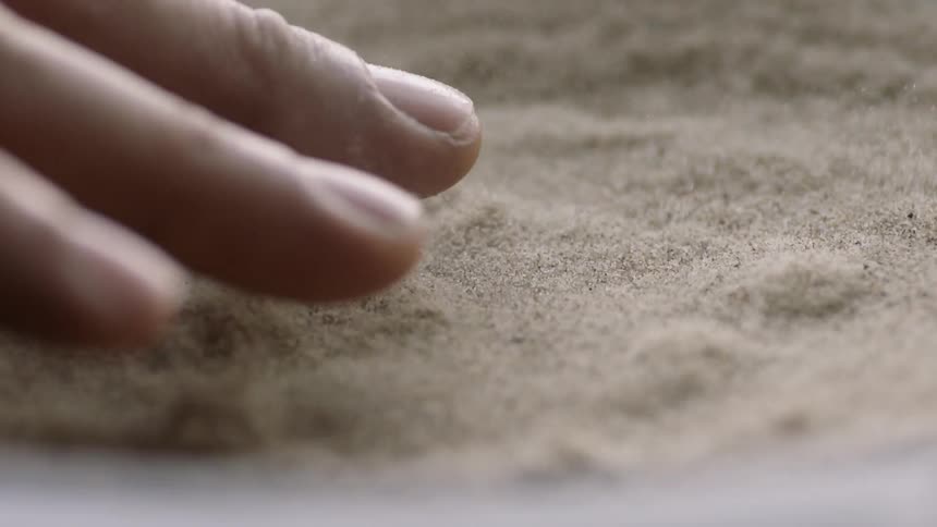 A person puts their hand over a sand filled speaker