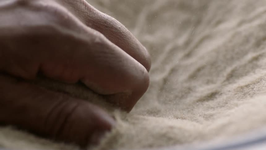 A man grabs a handful of vibrating sand