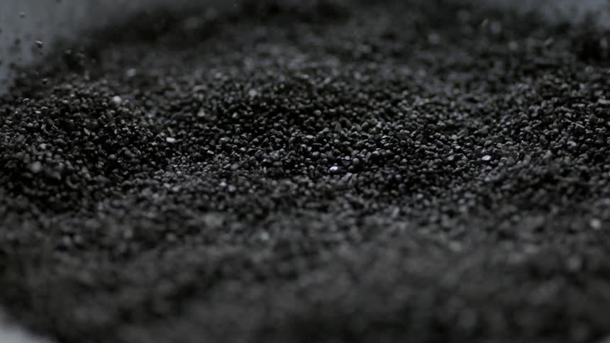 Black sand vibrates in a pile