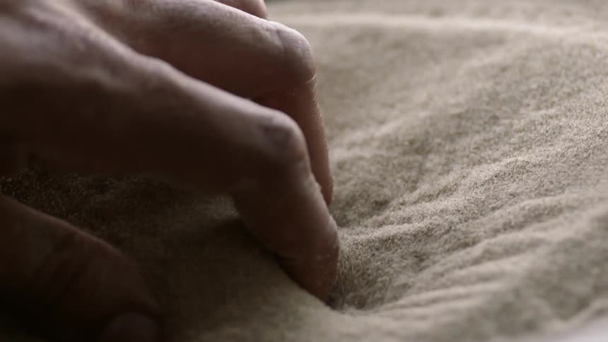 A person grabs vibrating sand