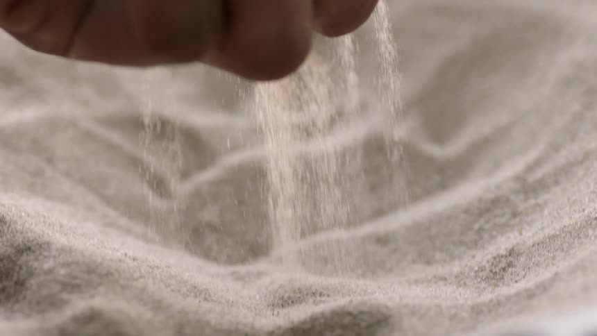 Sand sifts through a person's hand