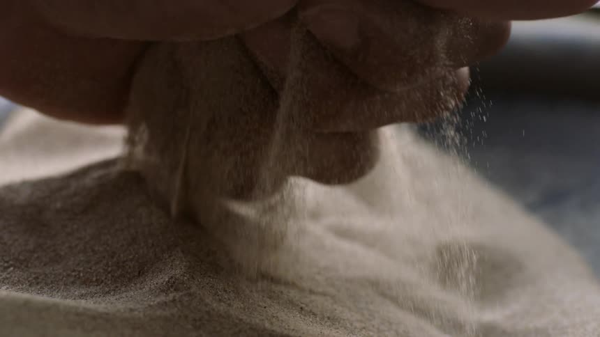 A man grips vibrating sand in his hand