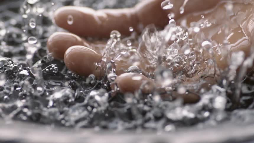 A person holds their hand in vibrating water