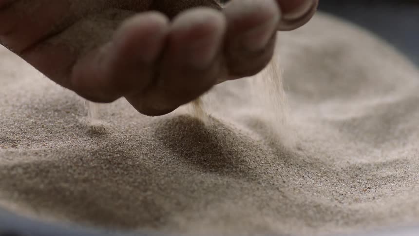 A person lifted sand and drops it on a speaker