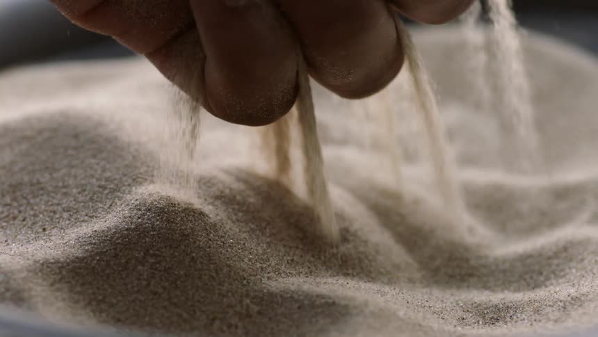 A person lets sand fall between their fingers