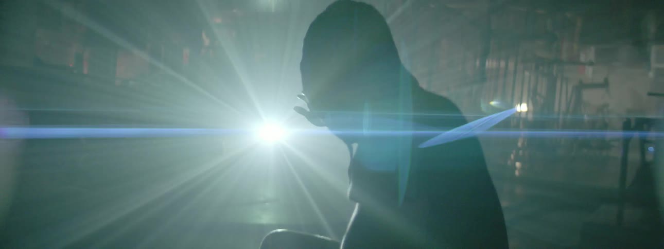 A man holds his hand toward a shining light as he sits outside at night
