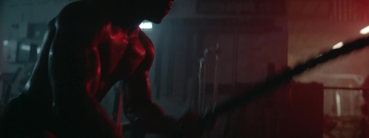 A man pulls ropes exercising in the dark gym