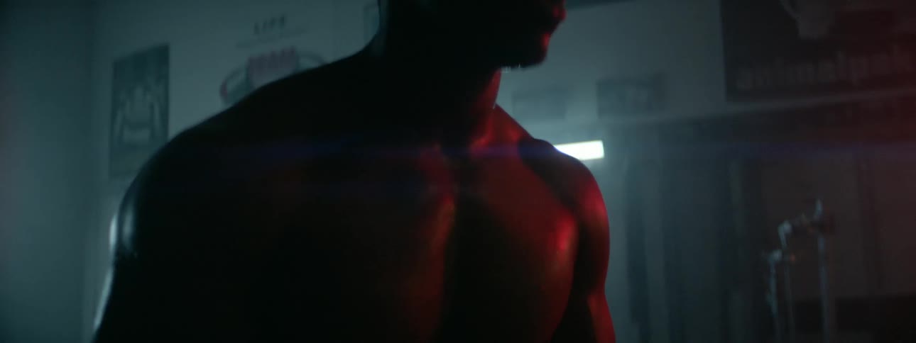 A man sweats inside a dark gym and catches his breath