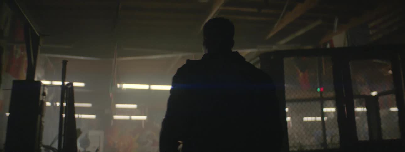 A man walks through a gym as the overhead lights turn on