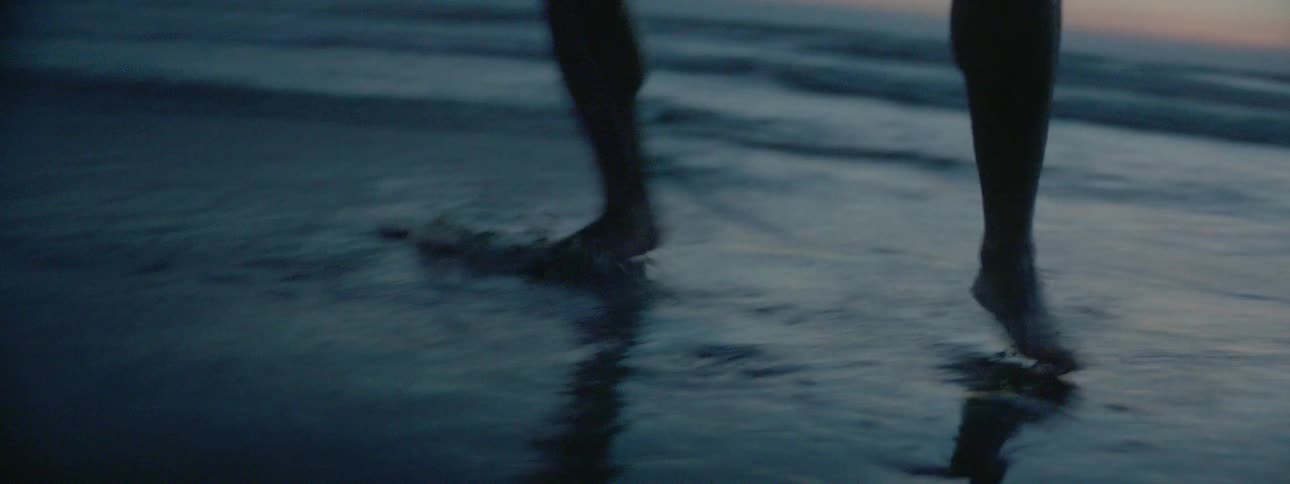 A man is practicing his fighting moves at the beach at dusk