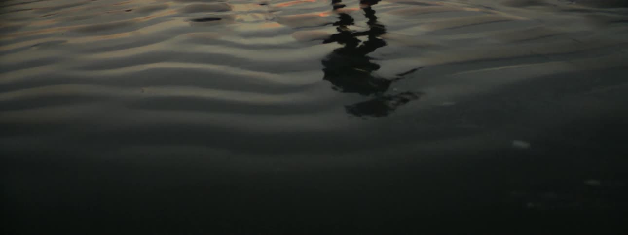 A man spins and kicks on a sandy beach at sunset