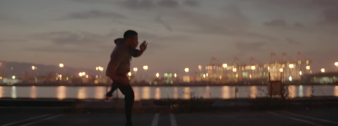 A man spins and kicks in a city at dusk