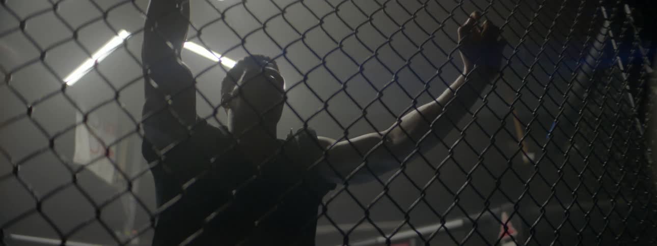 A man is leaning up against a cage breathing heavy