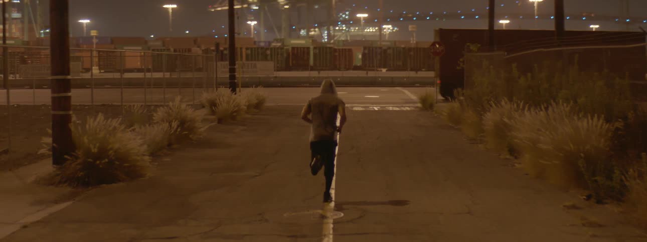 An athlete is jogging in an industrial area at night