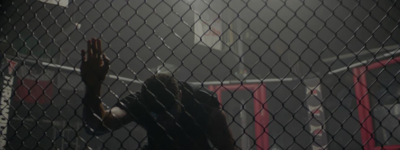 Fighter in an octagon kneels and catches his breath