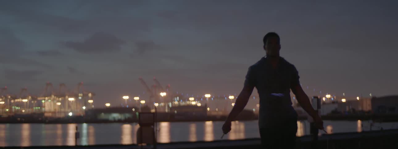 A man jump ropes on a bridge at dusk