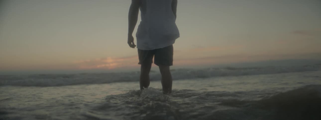 Man wading in sea at sunset