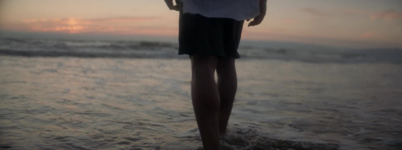 A man wades through the water on the beach