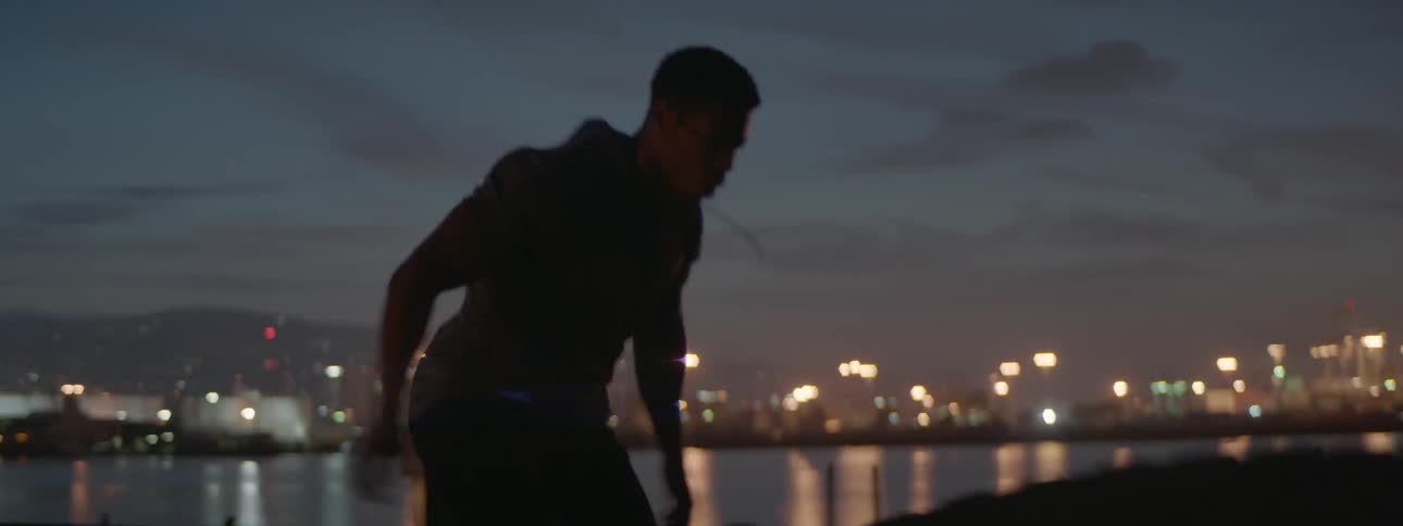 Man pushes a huge tire near a riverside at night