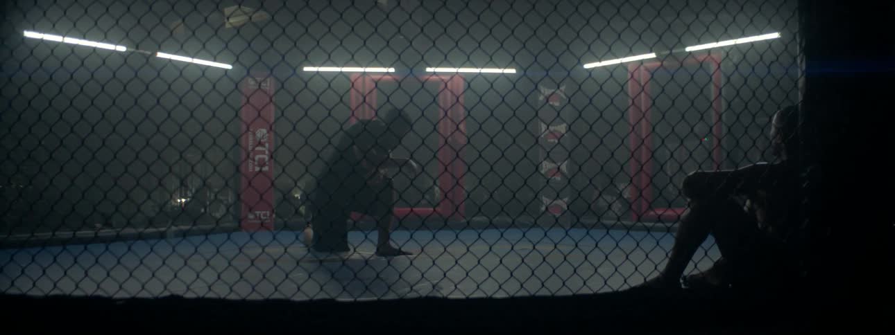 A man is kneeling in a fighting ring
