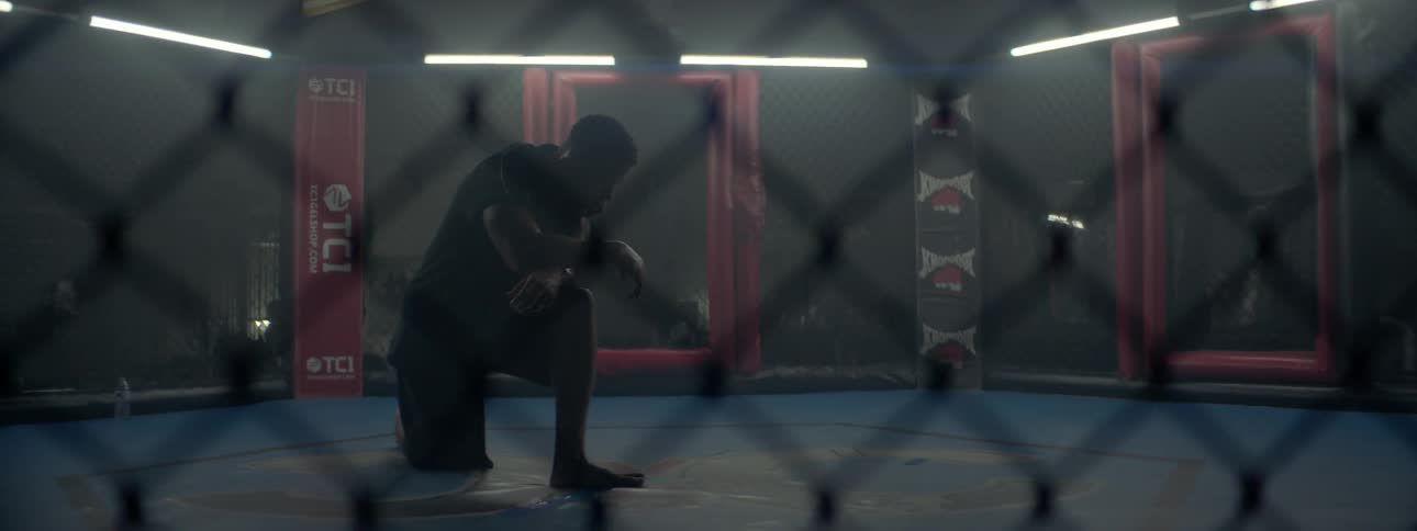 A man is down on one knee in an mixed martial arts ring