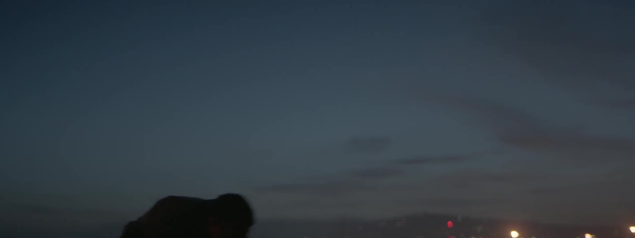 A man pushes a large tire outside at night