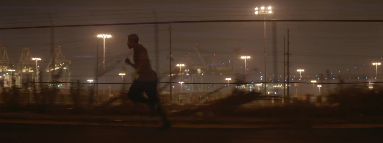 A man runs outside a fence at night