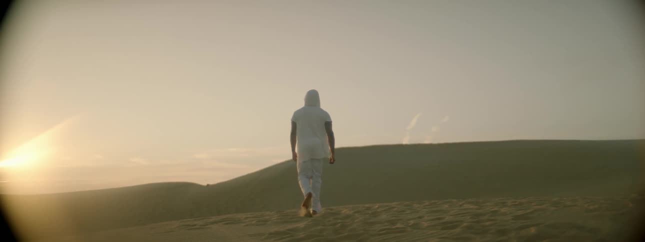 A man is walking amid sand dunes