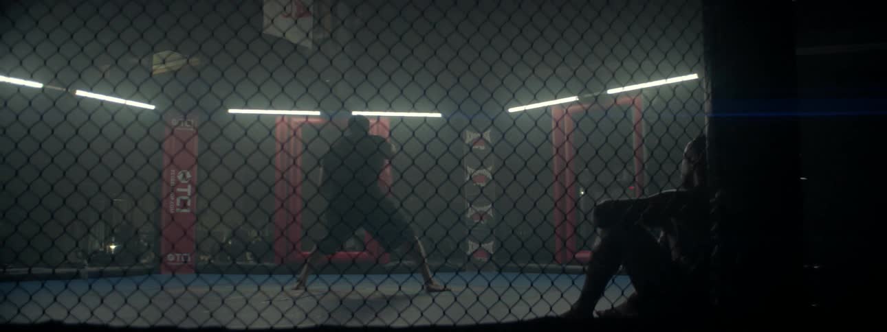 A fighter is going through his moves as he stands in a fighting cage in a gym