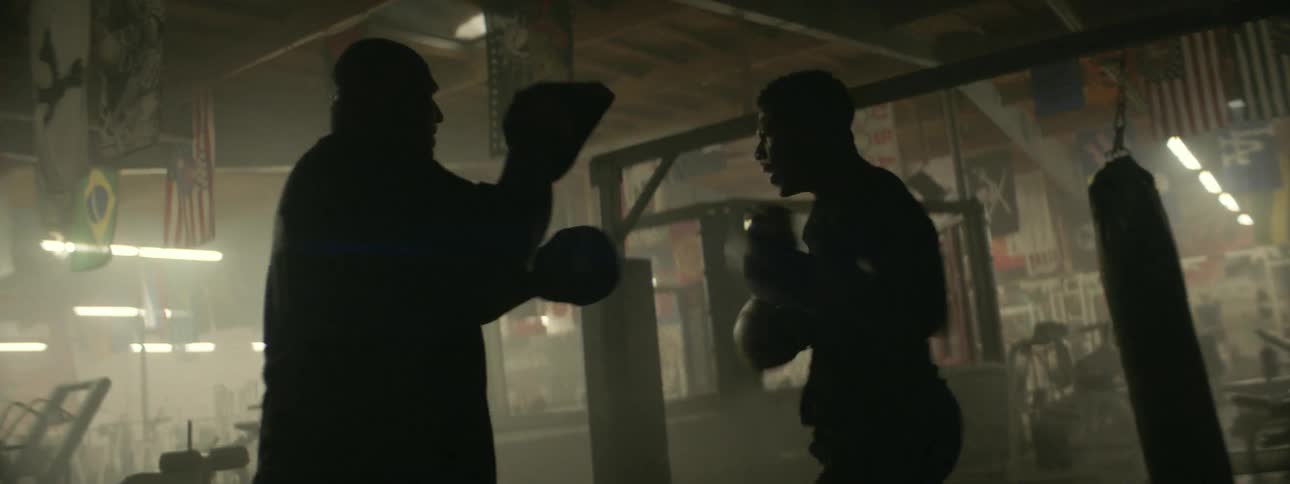 A boxer works with a trainer in a gym