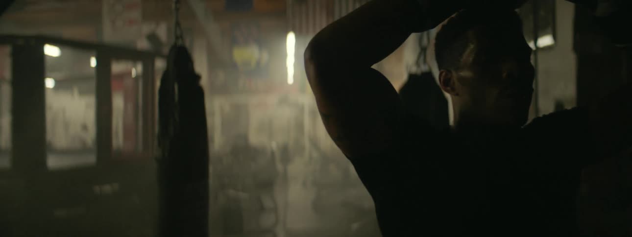 A boxer breathes heavily while taking a break in a gym