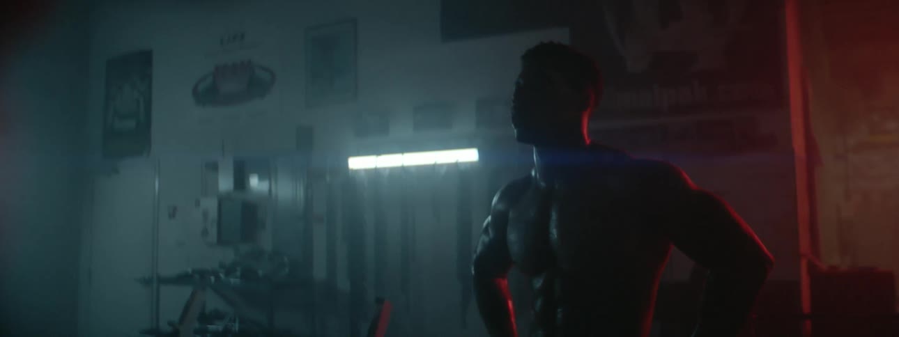 A man sweats inside a dark gym and catches his breath