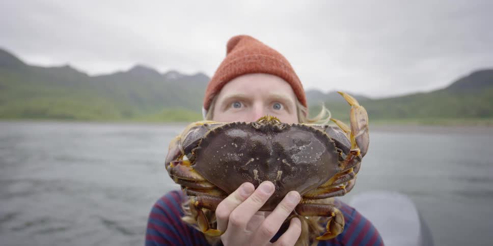 Man holds a crab while riding on a boat