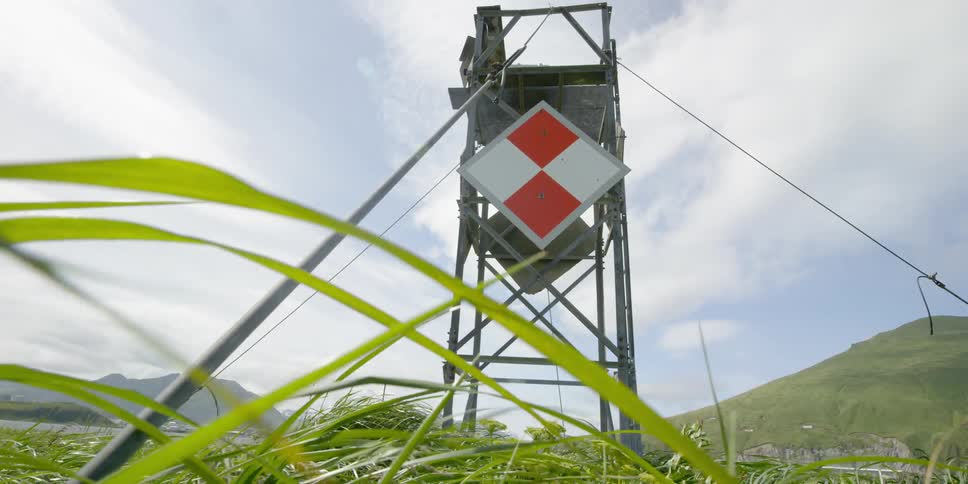 Wind blows through grass at the base of a tower